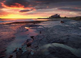 March - Sunsets behind Bamburgh castle – beach in foreground